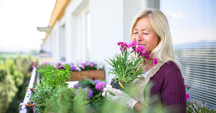 Older women smelling flowers on her balcony